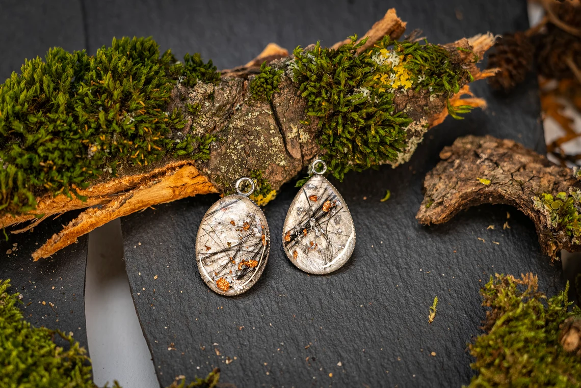 Umrahmt von natürlichen Materialien fügen sich diese extravaganten Ohrringe in ein harmonisches Gesamtbild ein.