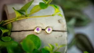 Traumhafte goldfarbene Ohrstecker mit einer echten lila Blüte. Eingefasst in Edelstahl.