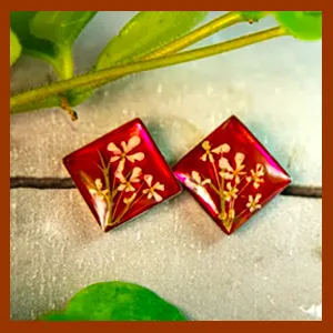 Zwei quadratische Ohrstecker aus rotem Epoxidharz und Edelstahl, verziert mit echten getrockneten Blüten.