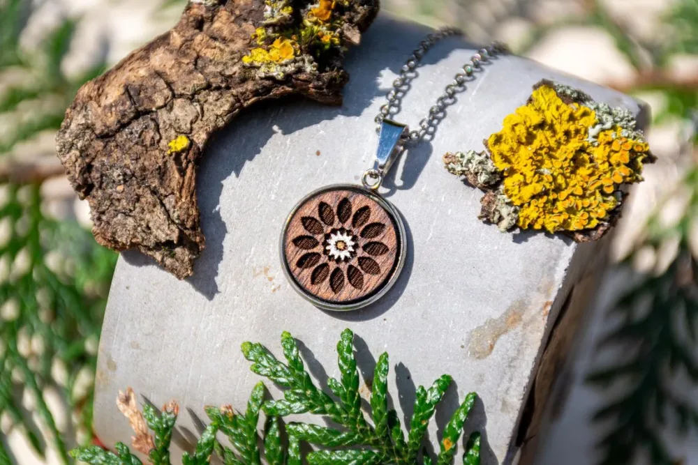 Runder Anhänger mit zarter weiss braunern Blume, handgefertigter Holzschmuck aus Walnussholz mit silberfarbener Fassung