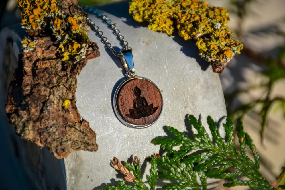 Handgemachter Holzanhänger mit Buddha-Motiv aus Walnussholz und Edelstahlrahmen.