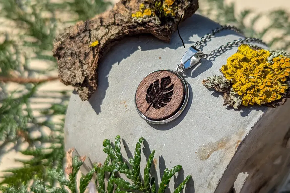 Holzanhänger mit Monstera-Motiv, rund, handgefertigt aus Walnussholz. Titel: Kette mit Monstera-Anhänger aus Holz