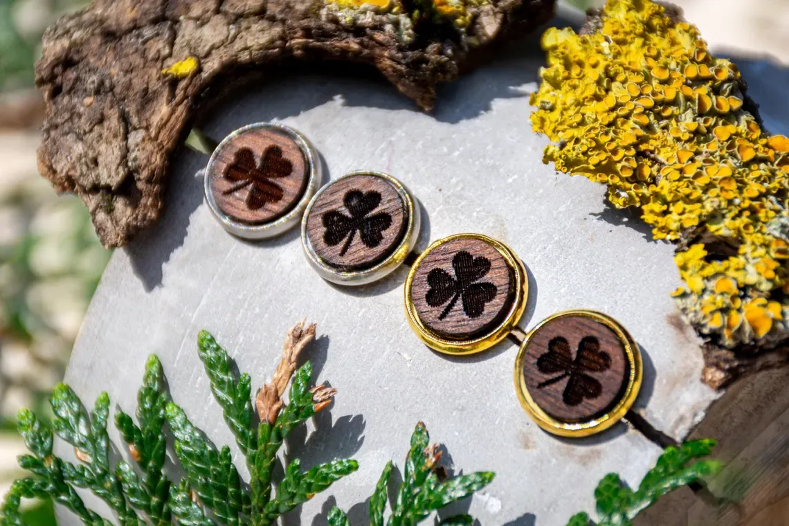 Ohrstecker aus Walnussholz mit eingebranntem Kleeblattmotiv, gold- oder silberfarbene Fassung.