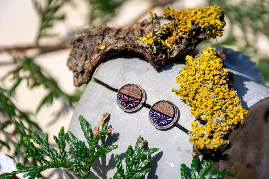 Ohrstecker aus Walnussholz mit lilafarbenem Ornament, silberfarbene Edelstahlfassung.